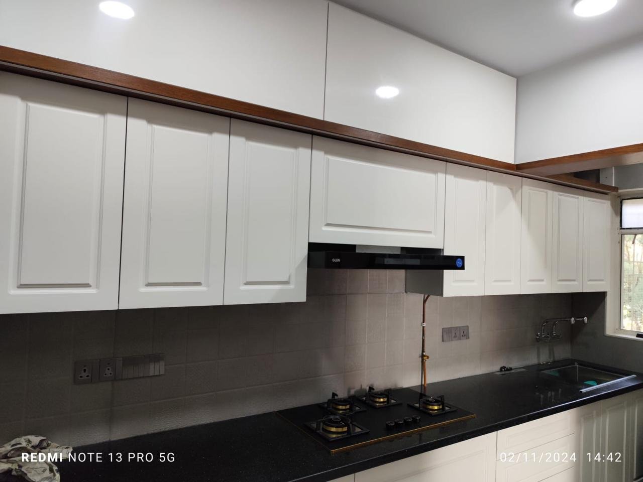 Modular kitchen in white shaker style with a wood cornice and black chimney