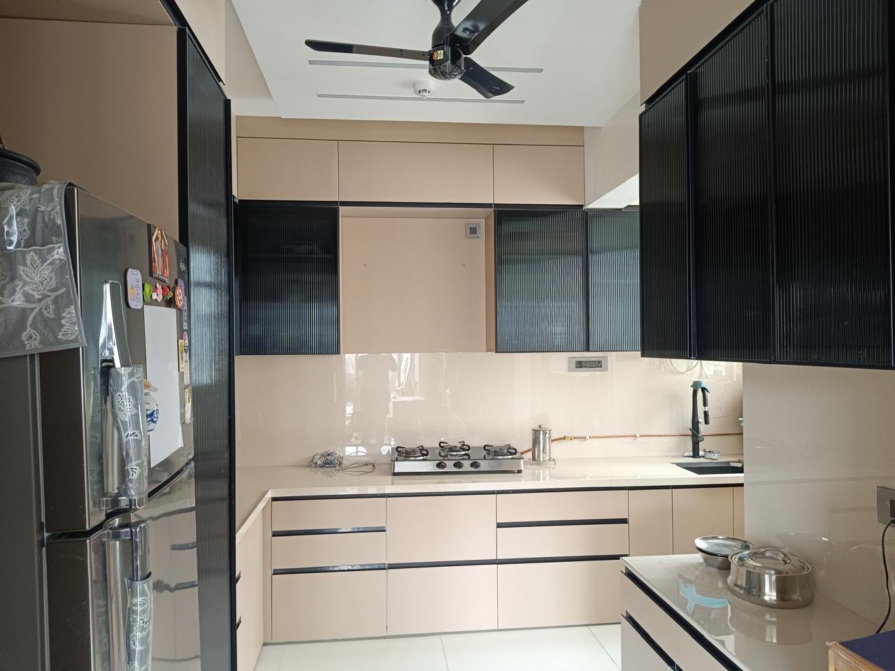 Parallel modular kitchen in beige with black fluted glass wall cabinets