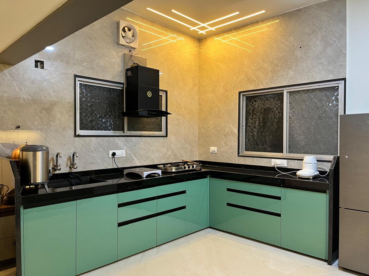 L-shaped modular kitchen in pastel green acrylic with a granite countertop