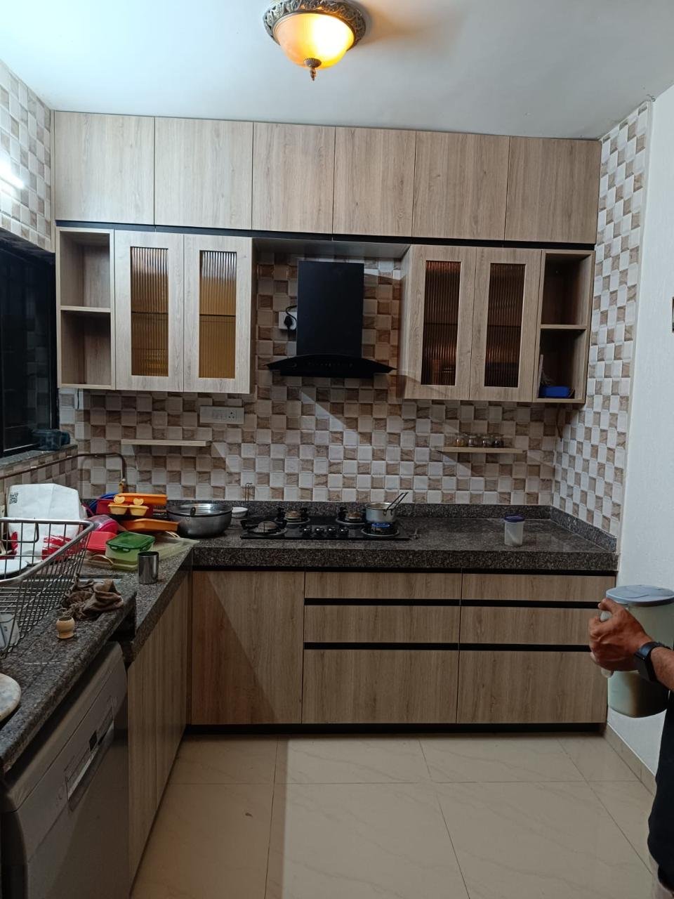L-shaped modular kitchen in wood-finish laminate with a stone-clad backsplash