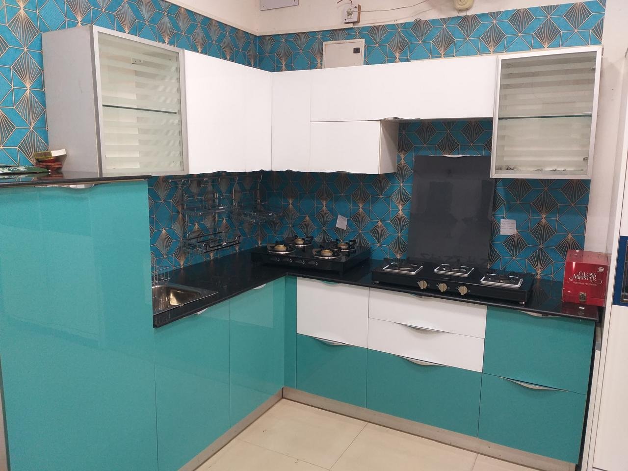 L-shaped showcase kitchen in teal and white with a geometric backsplash
