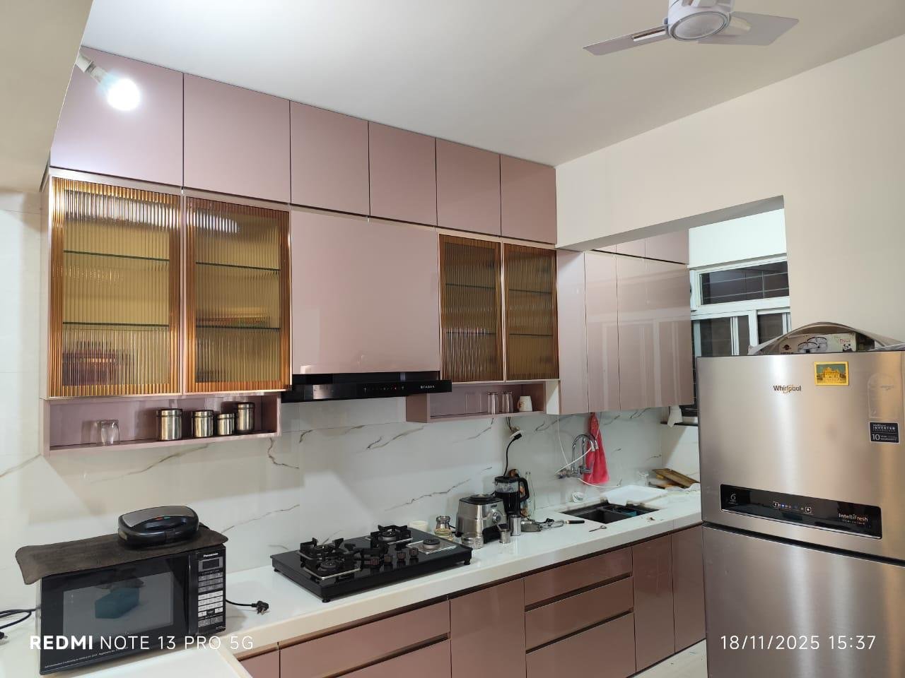 Modular kitchen in blush pink with fluted glass shutters and a marble backsplash
