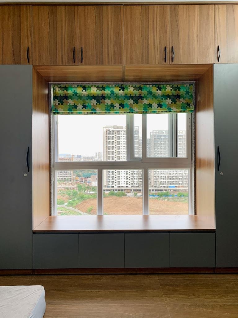 Window bay seating ledge with storage cabinets, framed by built-in wardrobes and overhead lofts