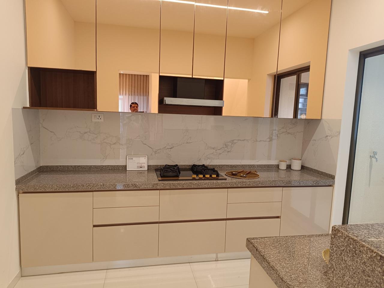 Modular kitchen in warm beige gloss with a marble-look backsplash