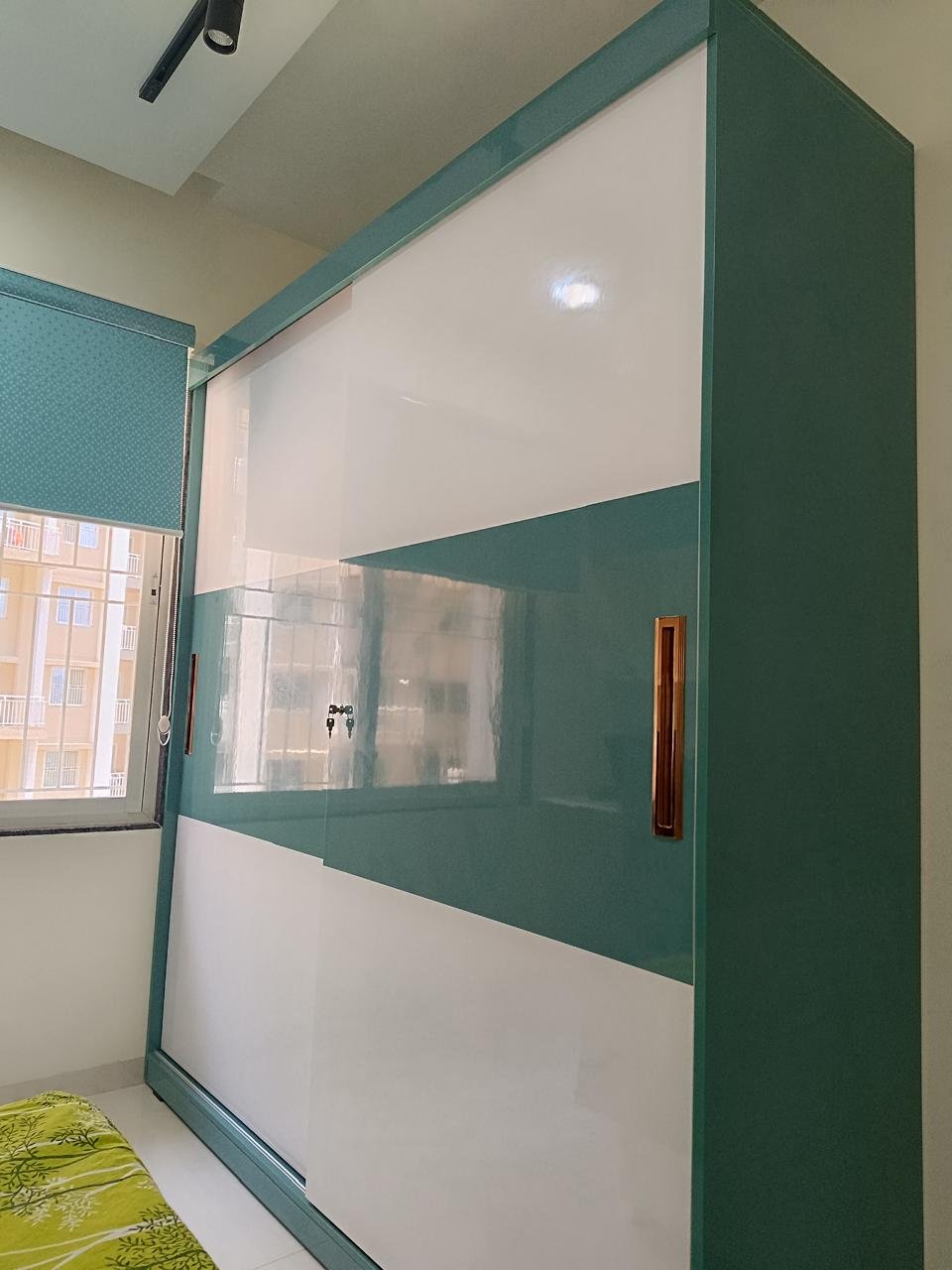 Gloss teal and white sliding wardrobe in a bedroom