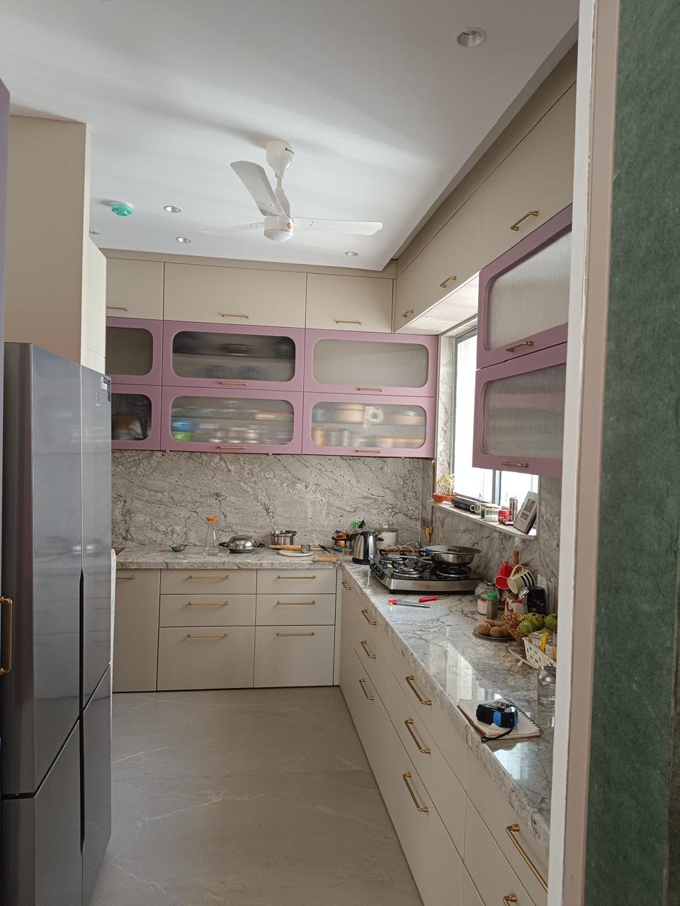 Modular kitchen in cream with pink glass shutters and a marble backsplash