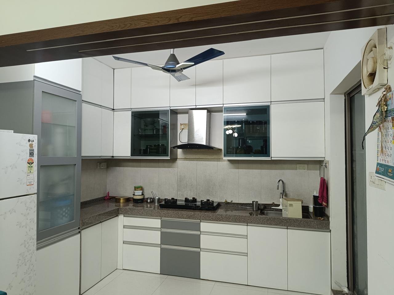 Modular kitchen in white with a frosted-glass tall unit and granite countertop