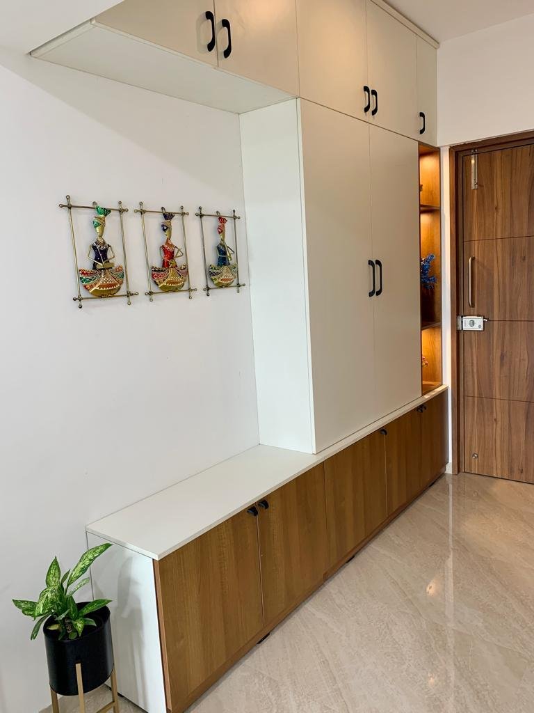Entrance storage wall with a low wooden shoe cabinet, a tall wardrobe and lit display shelves
