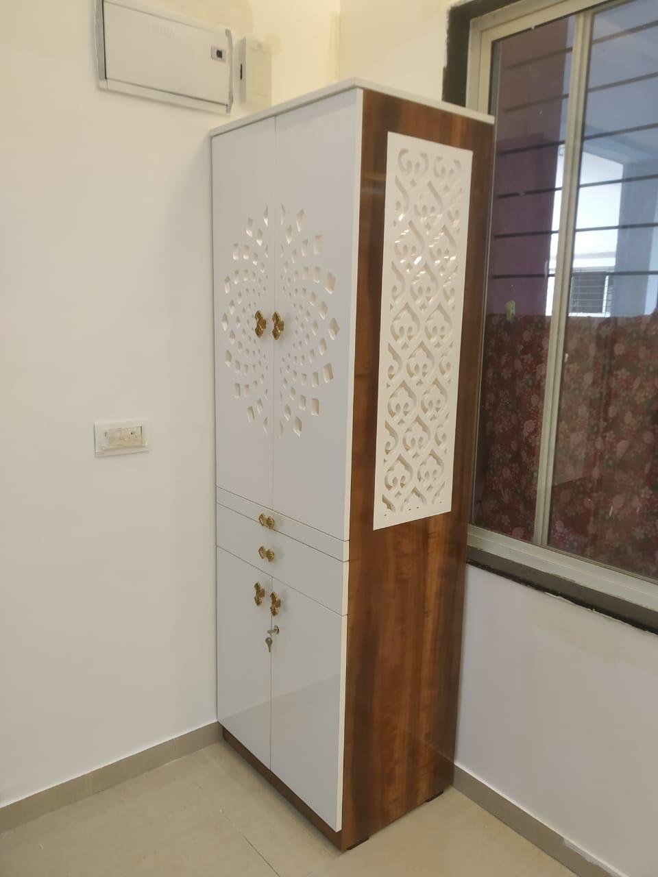 White cabinet with decorative jaali cut-out panels and brass handles