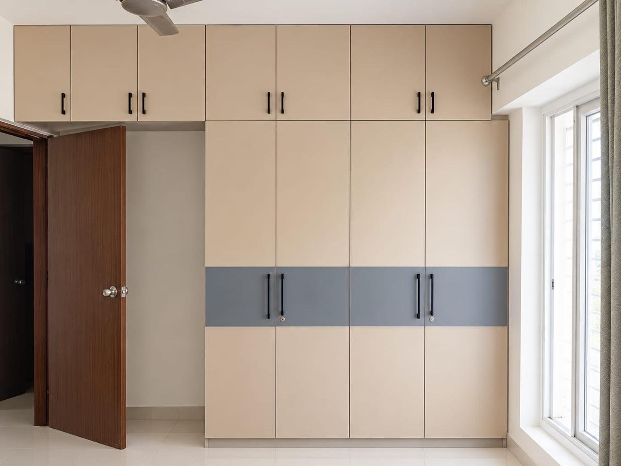 Built-in wardrobe in matte beige laminate with a slate-grey accent band and slim black handles
