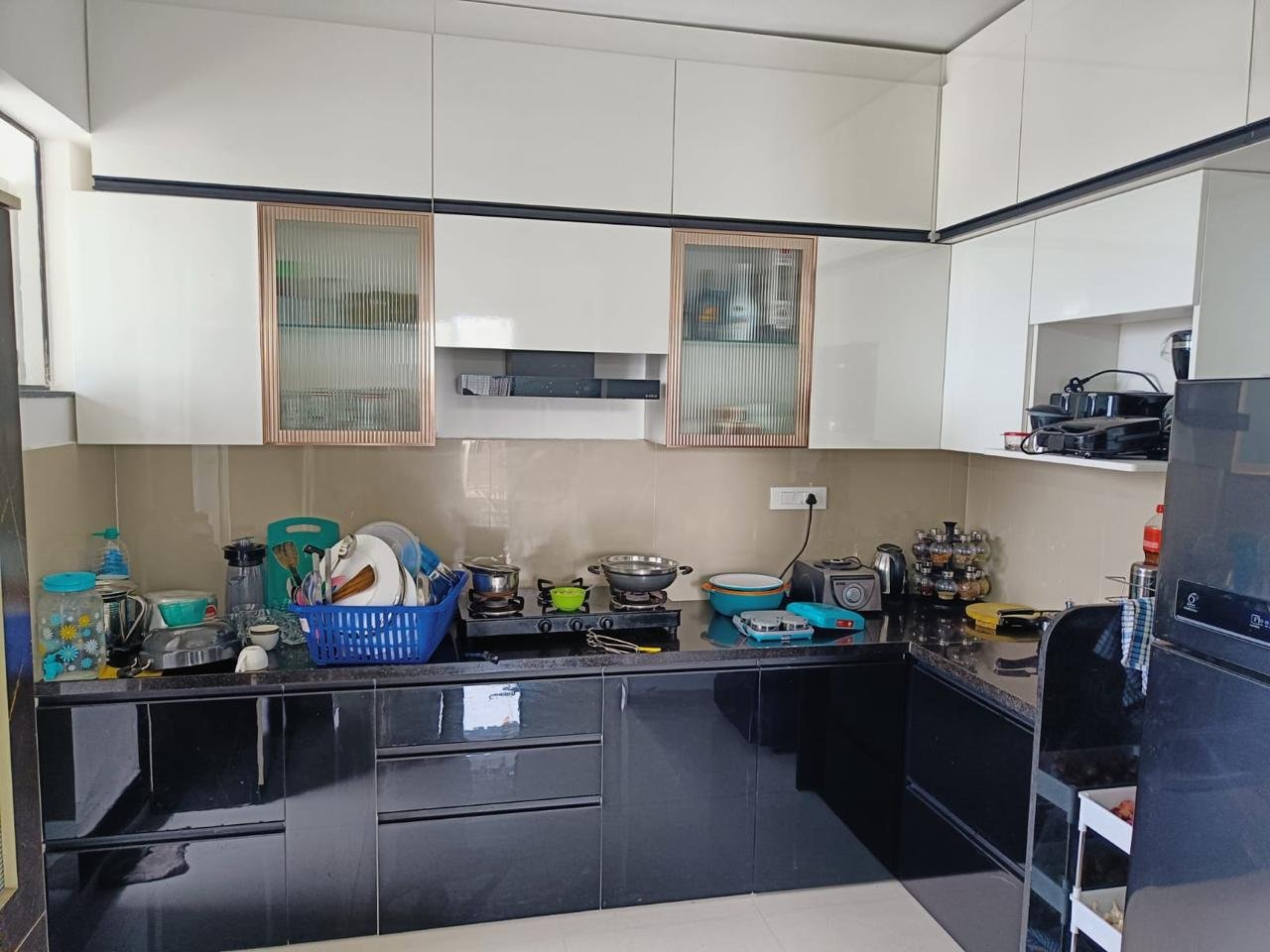 L-shaped modular kitchen in white laminate with black granite countertop